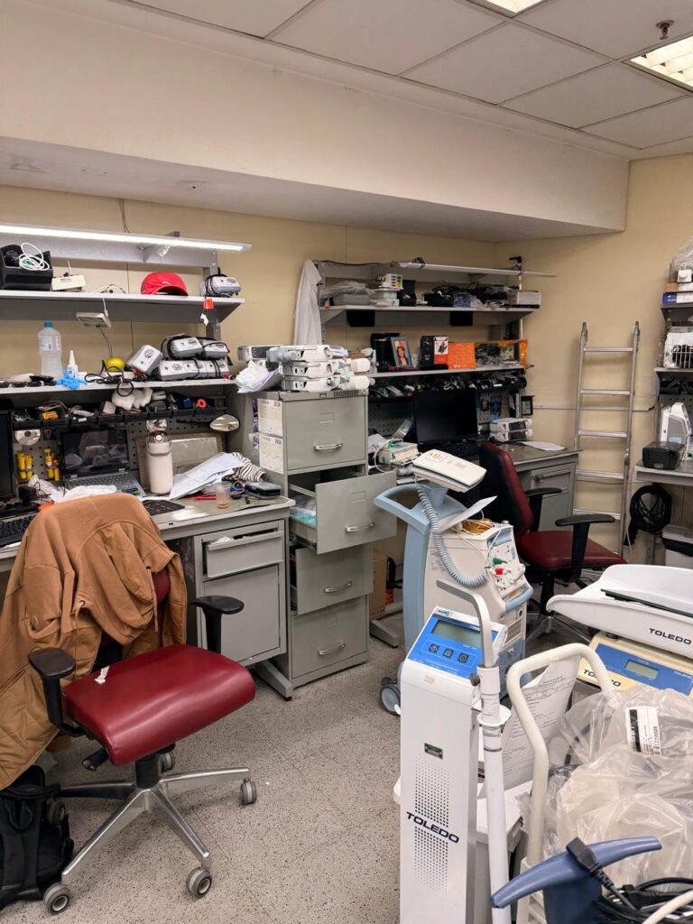 Oficina de engenharia clínica com equipamentos médicos em manutenção nas bancadas